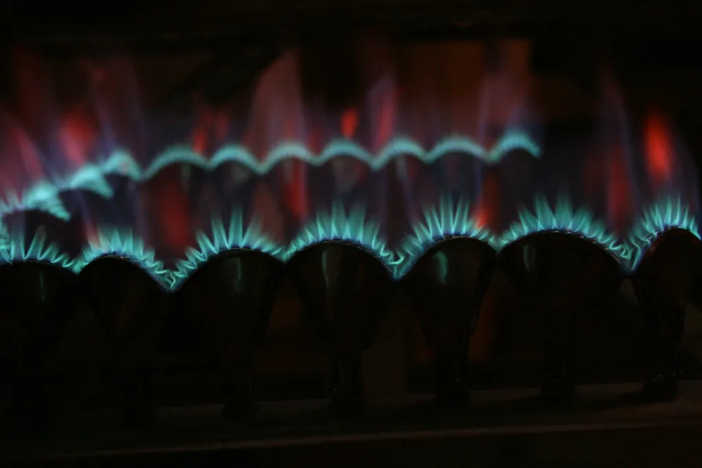 Blaue Gasflammen brennen in gleichmäßiger Reihe auf einem Gasbrenner