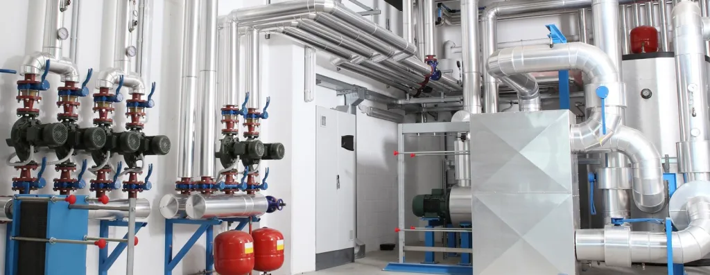 Industrielle Heizungsanlage mit blauen Rohren, Ventilen und Umwälzpumpen in einem Technikraum