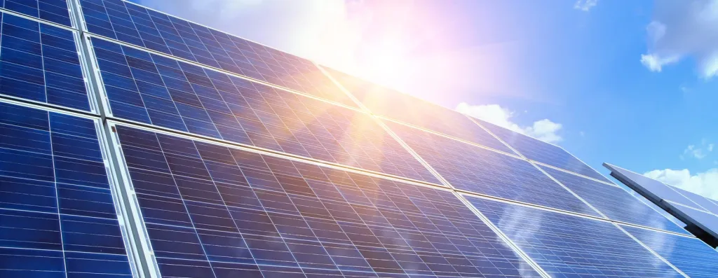 Blaue Solarpanele unter strahlender Sonne mit blauem Himmel und weißen Wolken