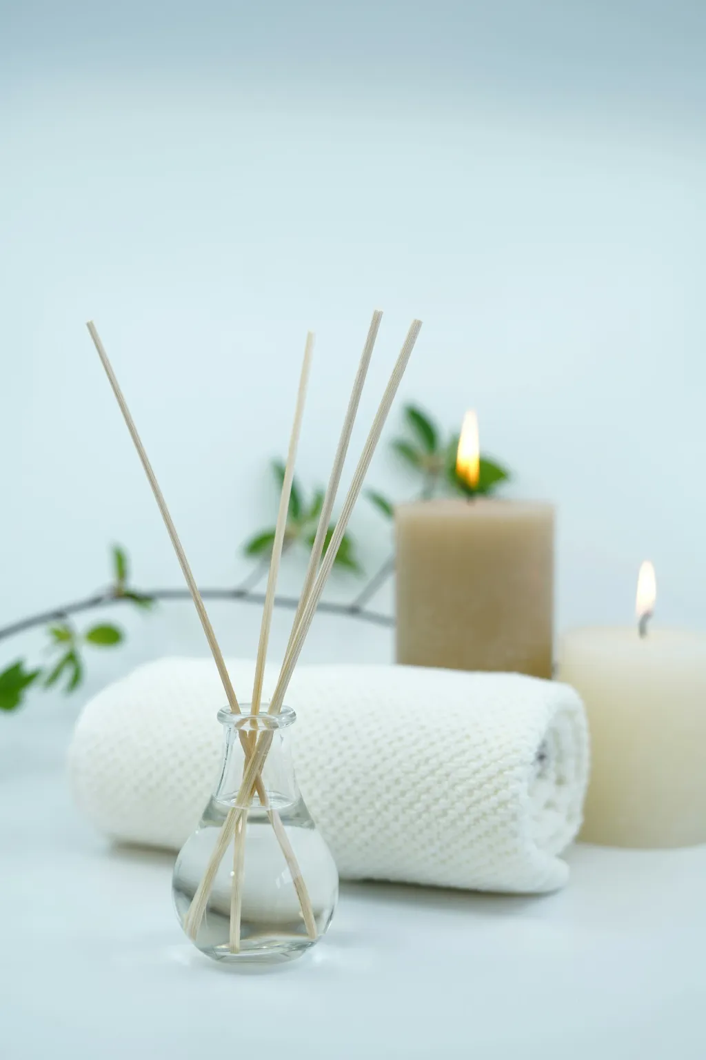 Spa-Atmosphäre mit Duftdiffusor, brennenden Kerzen und gerolltem weißen Handtuch