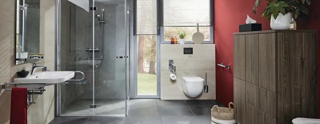 Barrierefreies Bad mit bodengleicher Dusche, roter Akzentwand und Holzmöbeln