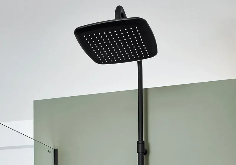 Schwarzer quadratischer Regenduschkopf mit moderner Duschstange vor grüner Glaswand
