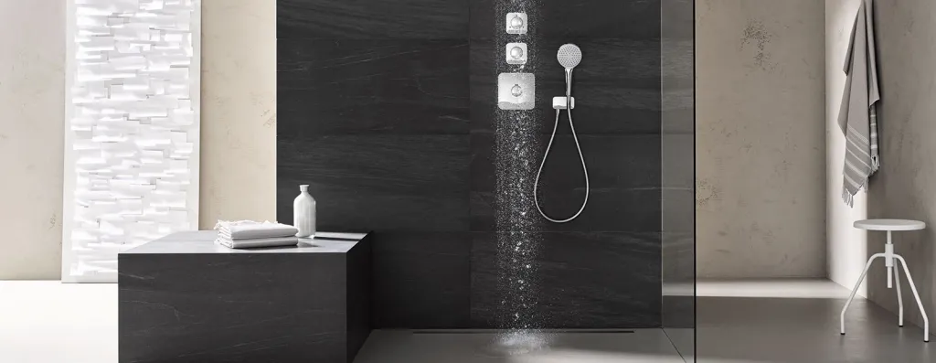 Fugenlose Dusche mit schwarzen Natursteinplatten und moderner Unterputzarmatur mit Wasserstrahl