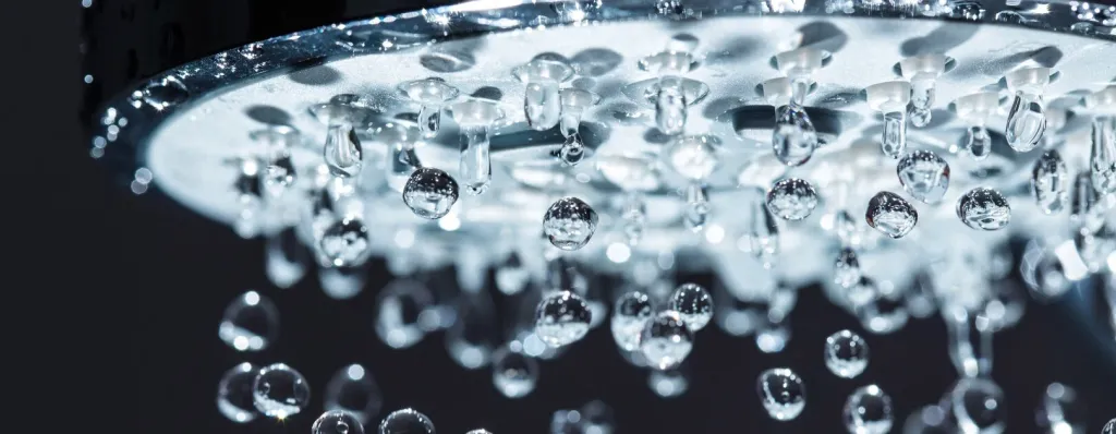 Nahaufnahme Duschkopf mit Wassertropfen vor dunklem Hintergrund