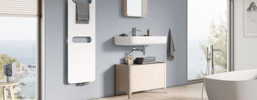 Helles Badezimmer mit weißem Designheizkörper, Waschtisch aus Holz und Meerblick durch große Fenster