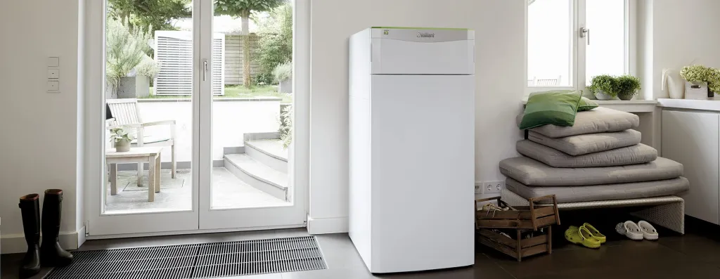 Weiße Wärmepumpe in hellem Hauswirtschaftsraum mit Blick auf Garten und Terrasse