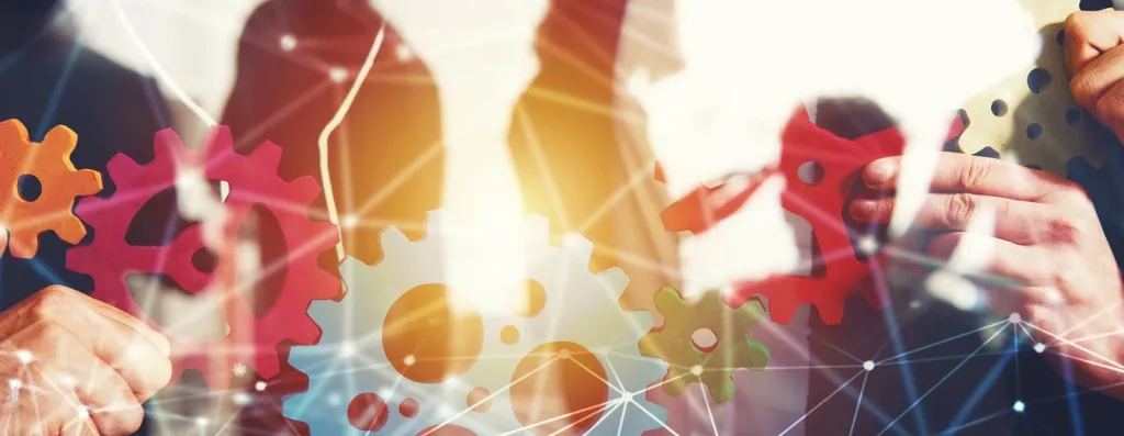 Business-Team hält bunte Zahnräder zusammen als Symbol für Partnerschaft und Zusammenarbeit